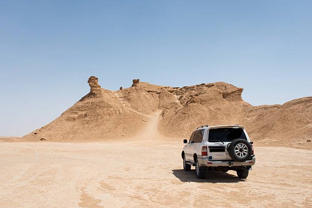 Off road car near Ong Jemel, the Camel Neck Rock, in the Sahara Desert near Tozeur, Tunisia. The film The english patient was filmed there.