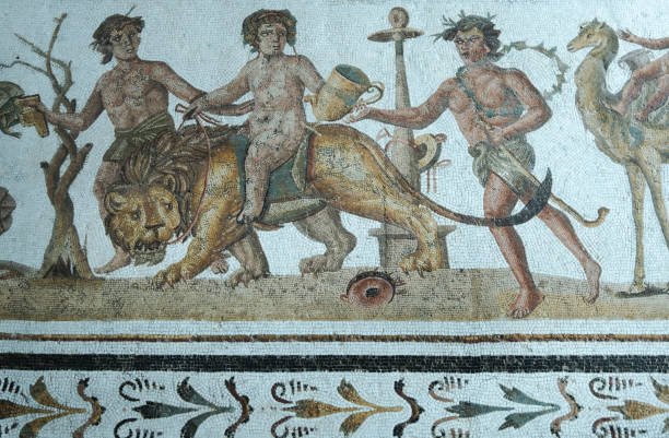 El Jem. Tunisia. View of a middle of the 2nd century AD stunning Roman mosaic now housed in the museum. It depicts Dionysus riding a lion. Around him, a Bacchante is dancing and playing the tambourine, two satyrs, Silenus is suspended on a camel, a panther and Mystis his nurse. Maison de la Procession Dionysiaque.
