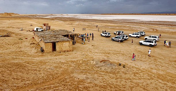 panoramic view of the iconic Mos Espa Star Wars filming location with tourist group and 4x4 vehicles parked in the desert plains of Ong Jmal. Shot on 08.10.2024